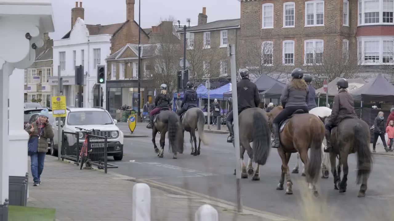 People riding on horses on public street in Wimbledon central London on a cloudy day