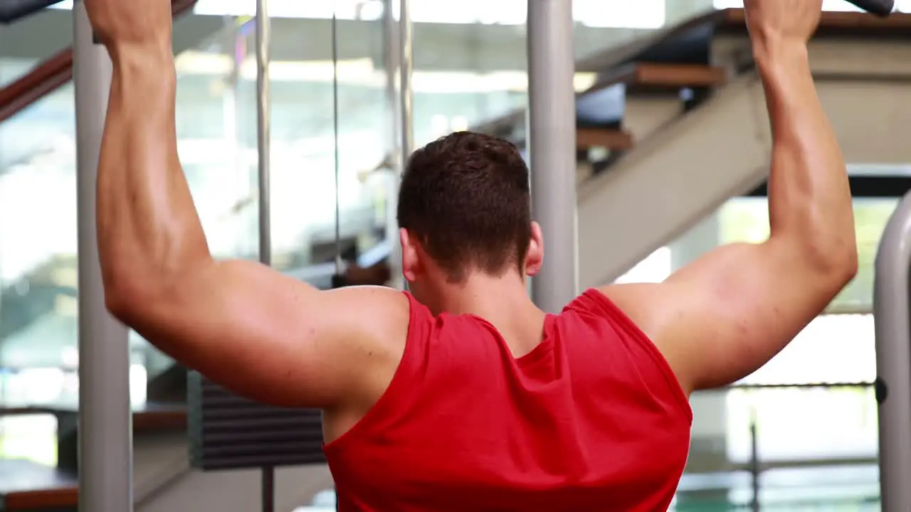 Fit man using the weights machine for his arms