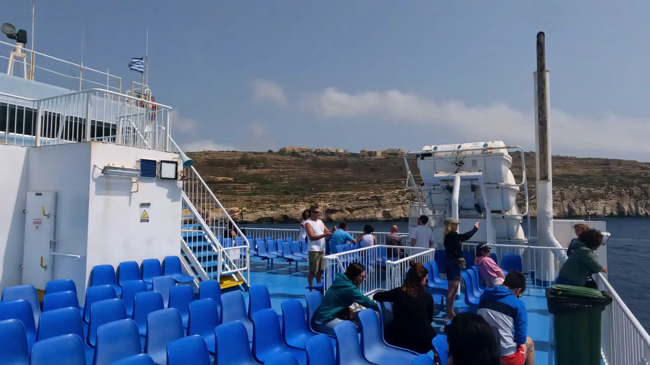 Ferry with blue seats and tourists taking photos of surroundings