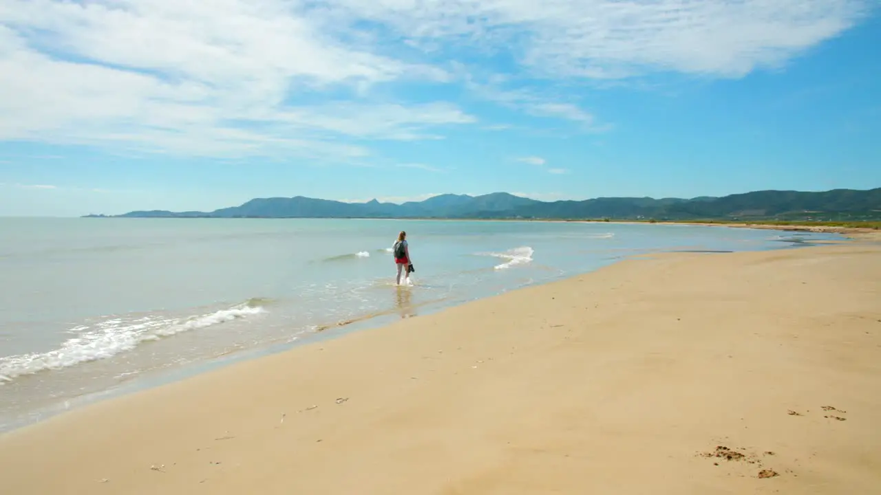 Young Woman At The Beach Walking In Shallow Sea Water Torrenostra Costa del Azahar Spain wide shot