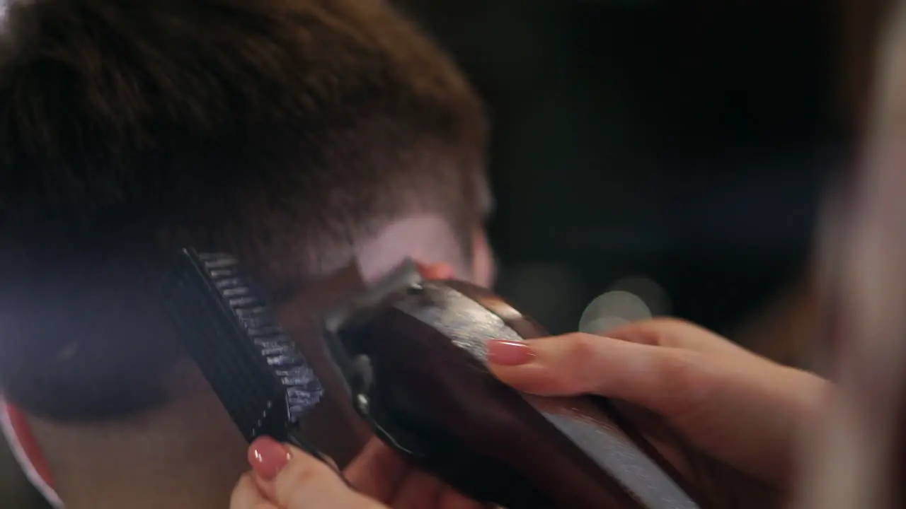 Close-up view on male's hairstyling in a barber shop with professional trimmer Man's haircutting at hair salon with electric clipper Grooming the hair