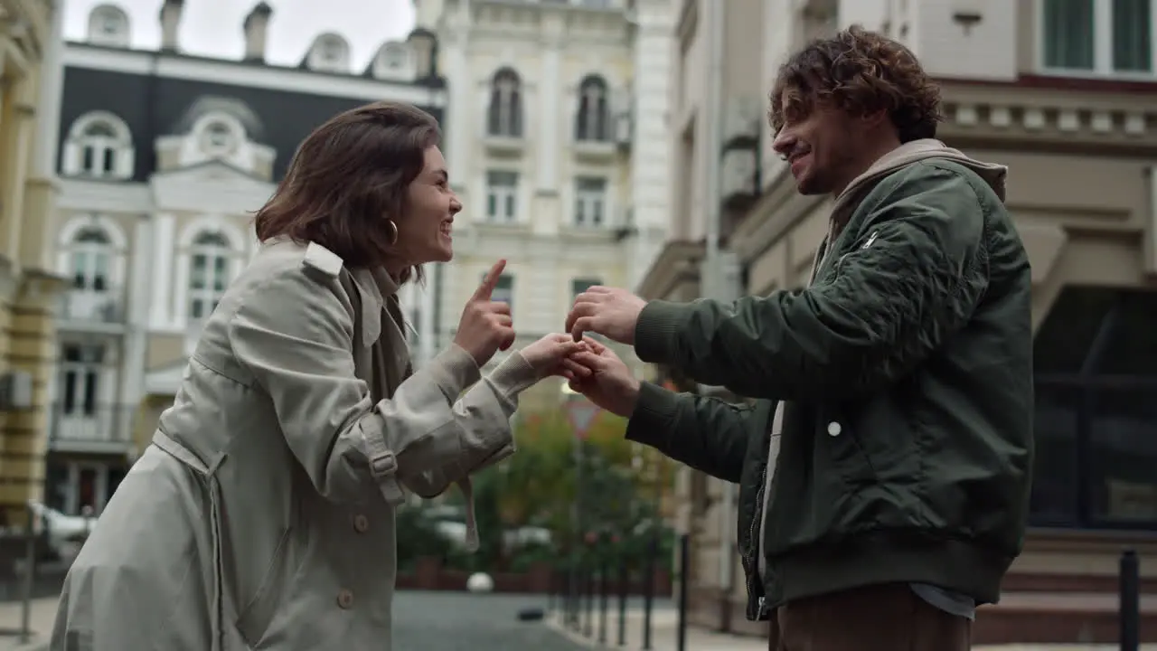 Cheerful couple having fun outside Woman and man dancing on urban street