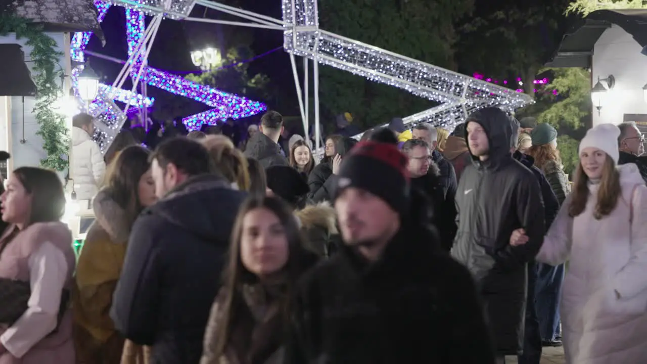 People Strolling During Holiday Season In City Park With Colorful Display Lights In Galati Romania