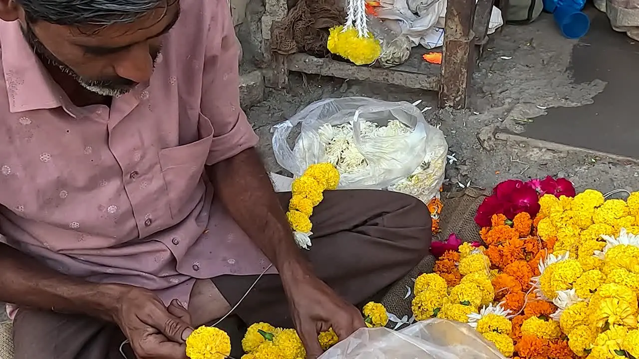 front view a shopkeeper is making fresh flower garlands on the street road