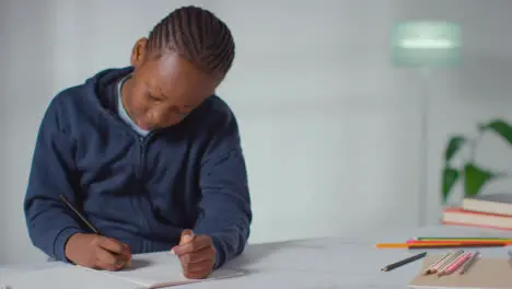 Niño Con Espectro De Asd En La Mesa En Casa Concentrándose En Escribir En El Libro Escolar