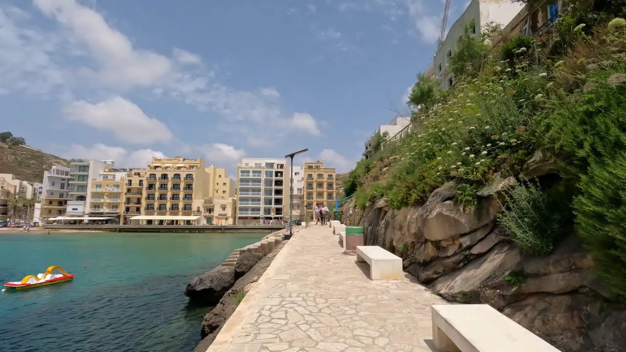 POV walking down a stone path towards waterfront hotels in Malta