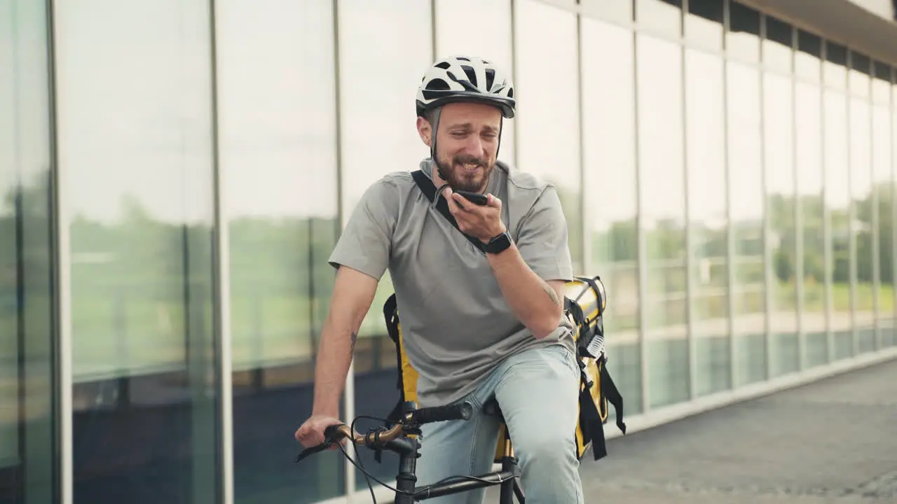 Fröhlicher Essenslieferant Mit Thermorucksack Auf Seinem Fahrrad Der Eine Audionachricht Mit Seinem Smartphone Sendet