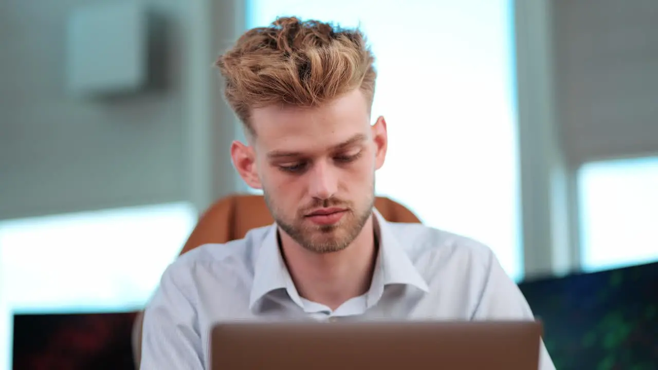 Young Businessman Sits Alone Concentrated on Notebook Tasks in modern office