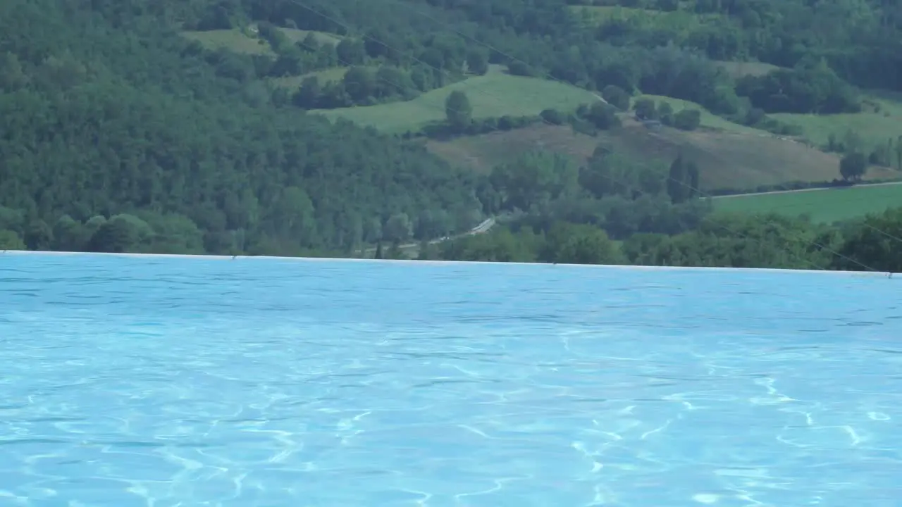 Luxurious infinity pool on the hillside of remote resort with on the background a leaving vehicle