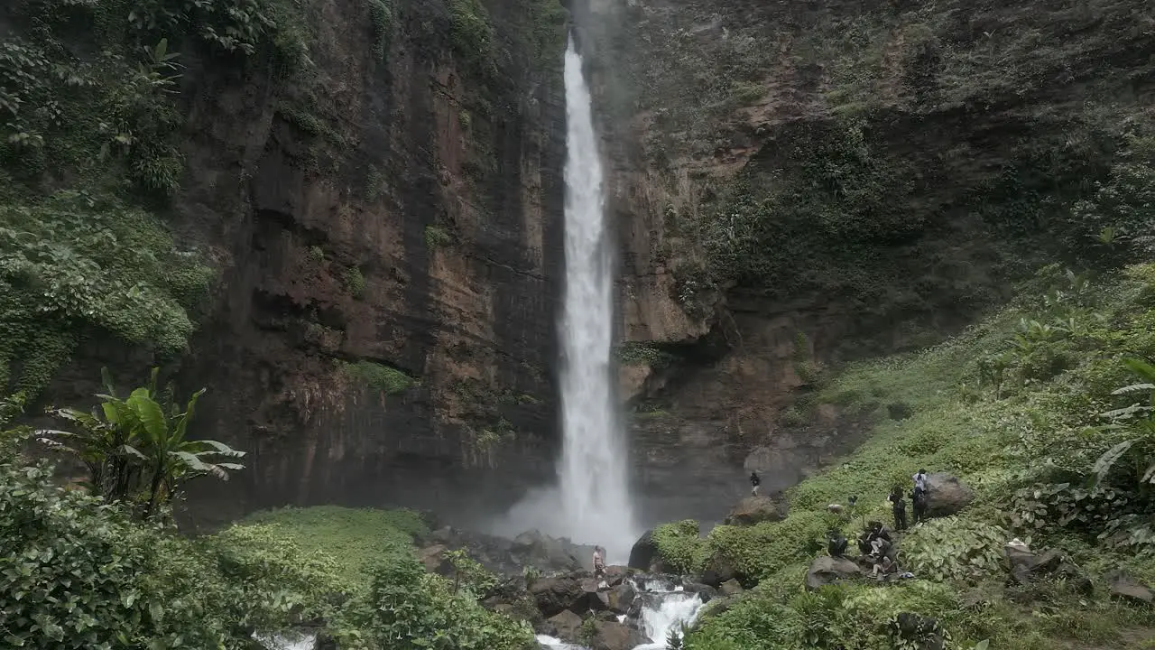 Aerial orbit Tourists gather below powerful Kapas Biru Waterfall Java