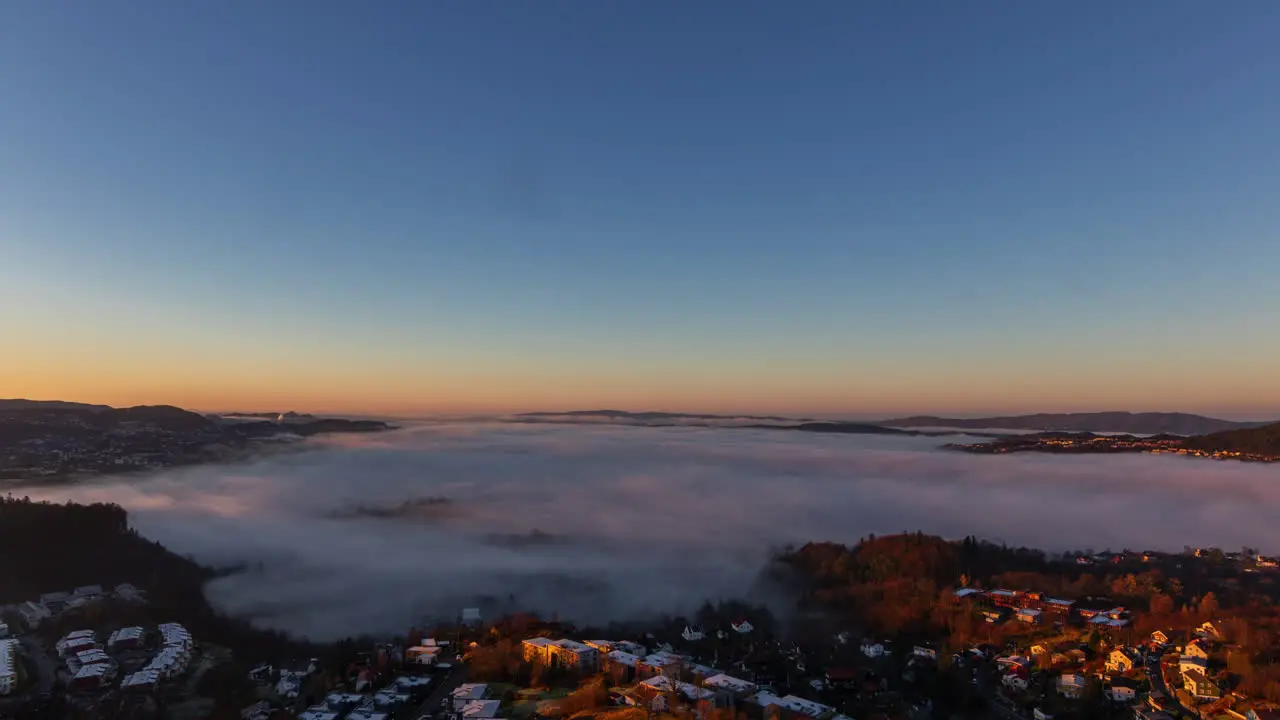 Timelapse of inversion clouds rolling around in urban valley between hills