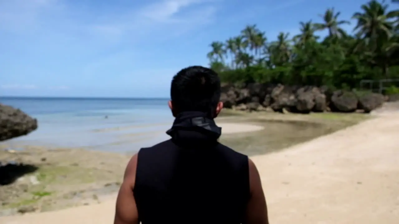 Back view of man walking on the beach and go for a snorkel