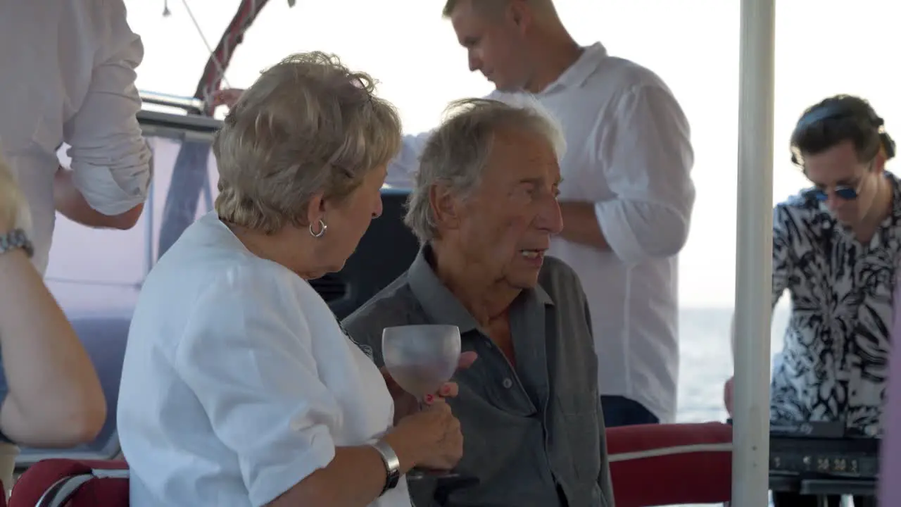 Older couple talk to each other on a sail boat wedding party