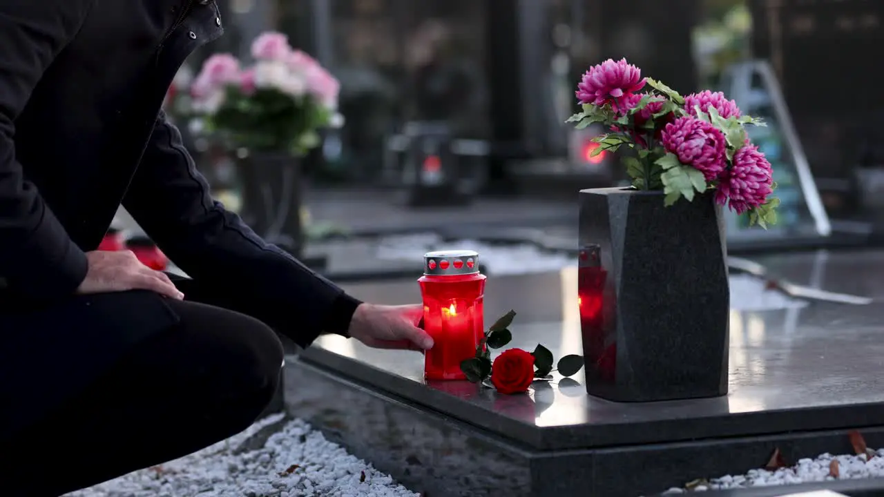 Man placing a candle on the grave