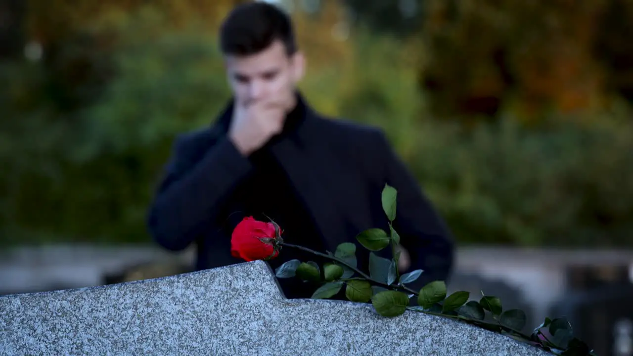 Man standing in front of a grave sad