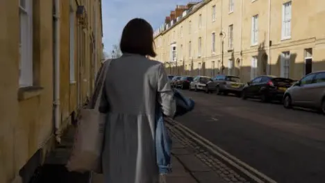 Tracking Shot of Young Woman Walking Around Quiet Street Corner