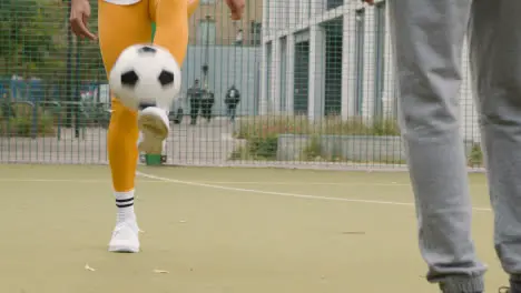 Close Up Of Artificial Soccer Pitch In Urban City Area With Young Couple Kicking Football 