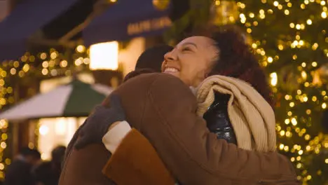 Loving Couple Hugging Walking Along Street On Christmas Shopping Trip To London 