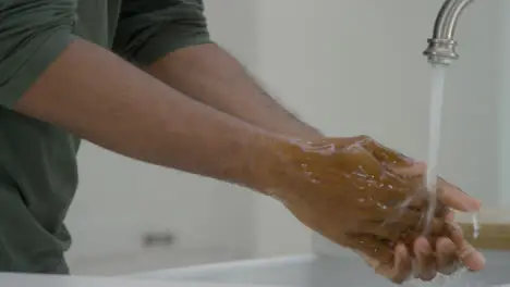 Man Cleaning His Hands with Soapy Water Under a Running Tap 