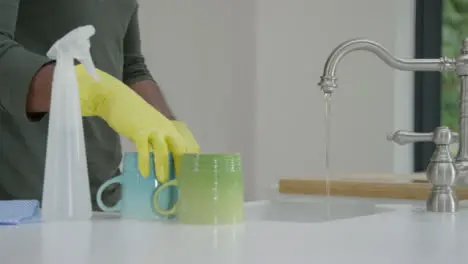 Man Cleaning a Mug Under Running Water from Kitchen Tap 