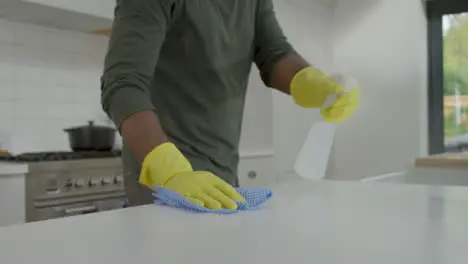 Man Cleaning Kitchen Work Surface with Rubber Gloves and Disinfectant