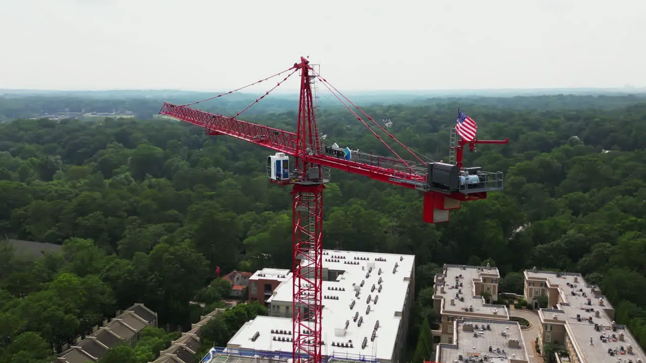 Orbit shot around red tower crane above construction site of modern multistorey building in urban borough