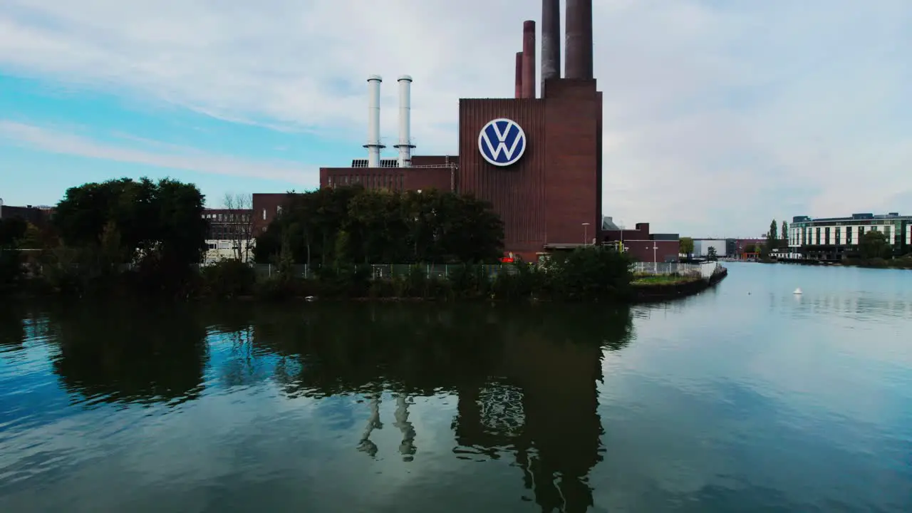 Drone taking off rises above Wolfsburg Volkswagen plant with casual man walking