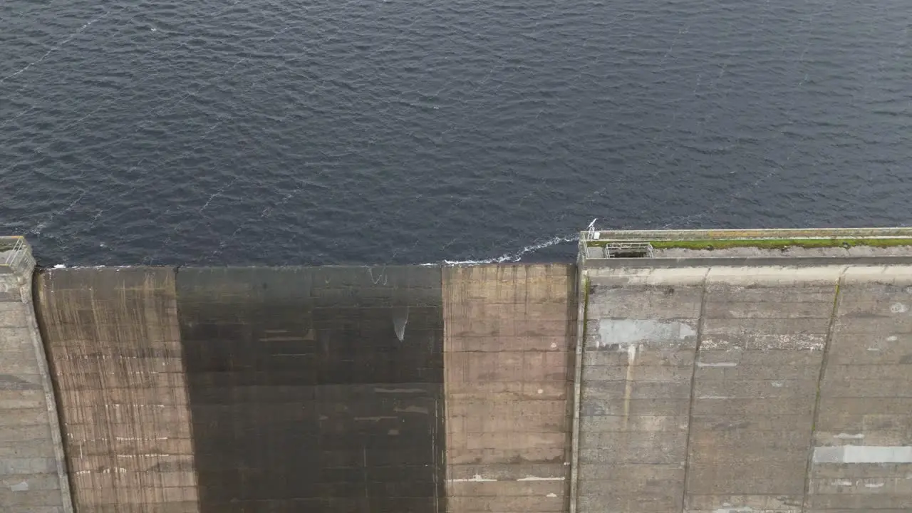 Booth wood reservoir aerial view close up on lake water supply splashing over concrete dam spillway gate