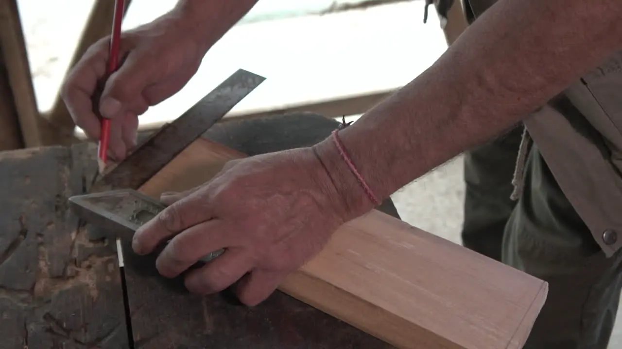 Taking measurements of wood piece with line and pencil