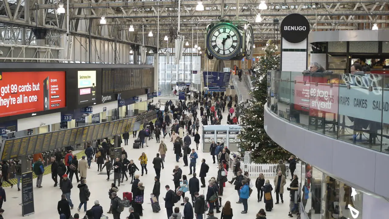 Holiday travel large crowd of people moving throughout Waterloo train station at Christmas time still shot