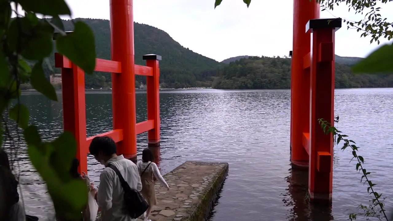 Slow motion push out between trees at Hakone Shrine with tourists taking pictures