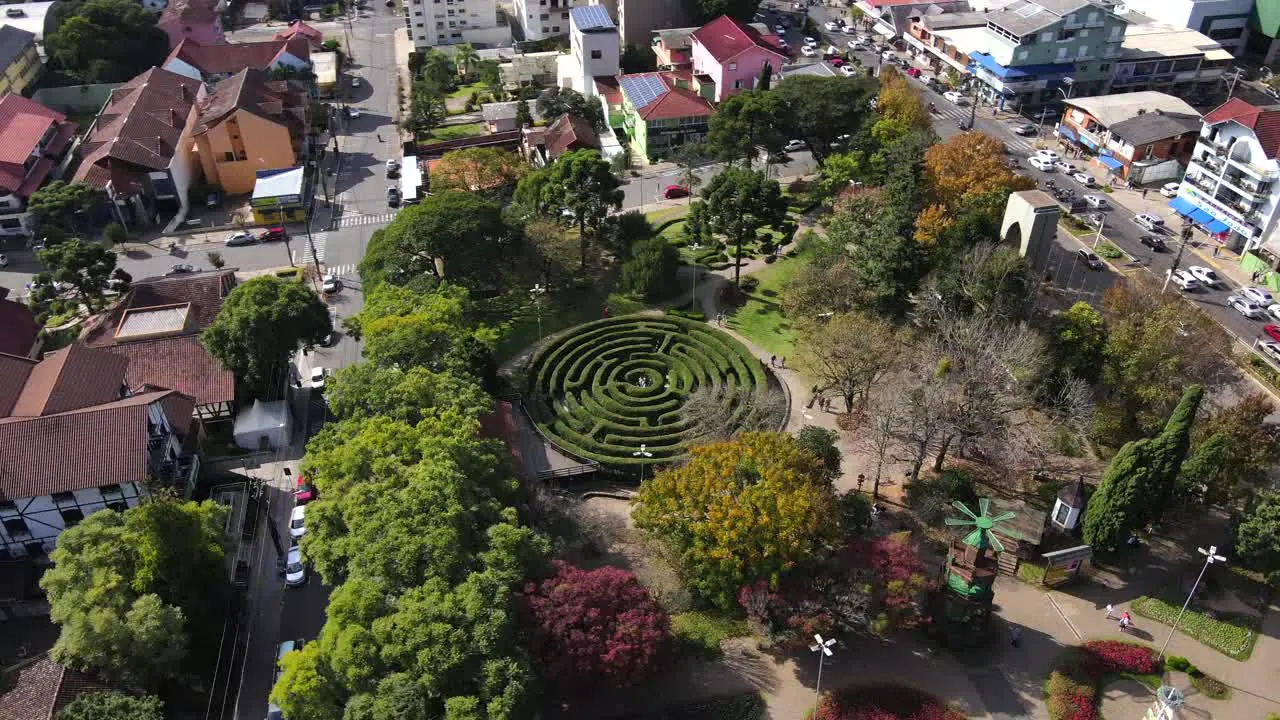 Orbital Aerial View of People playing in a Green Maze Labyrinth in a sunny day