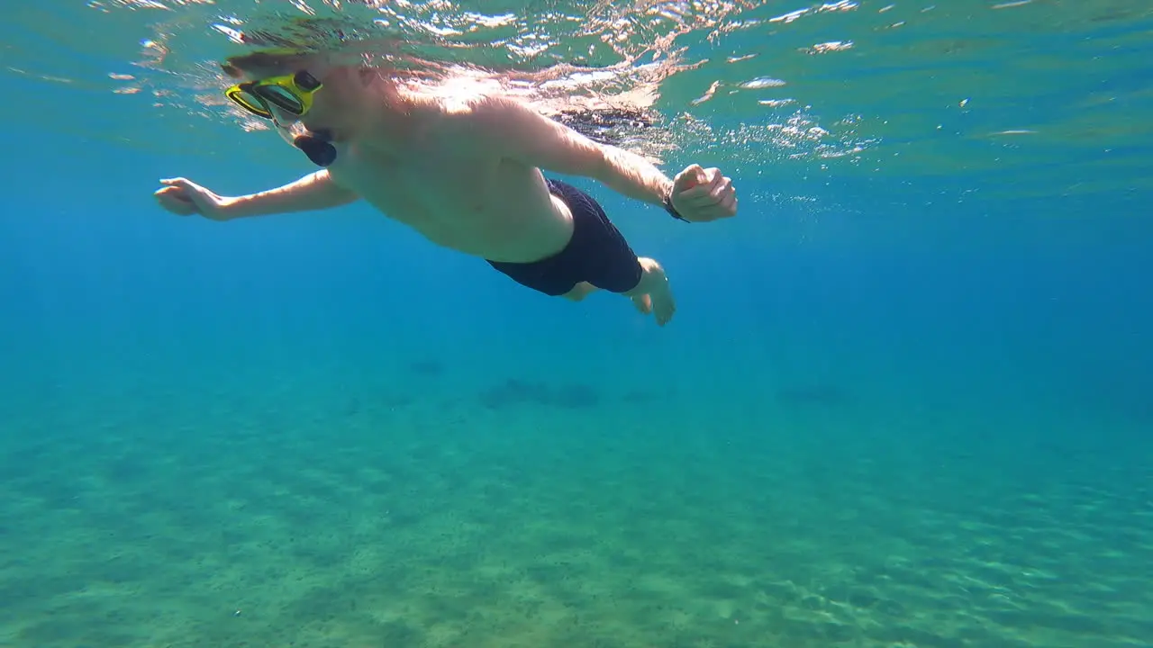 A young scuba diver swims on the surface of the Mediterranean near a beach on a Greek island underwater view