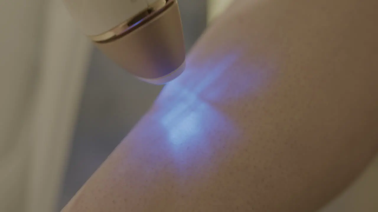 Extreme Close Up Slow Motion of a Woman Using an Intense Pulsed Light Hair Removal Device on Her Leg