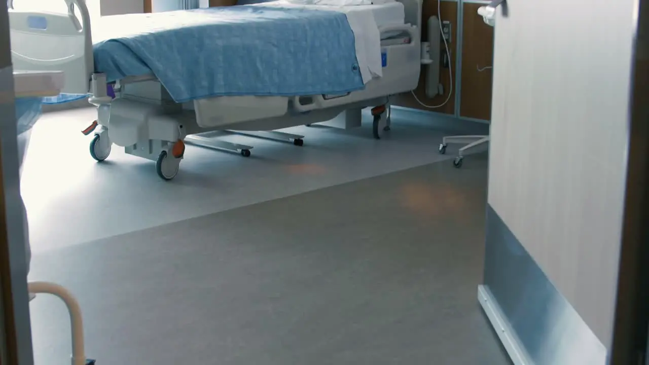 Tilt up through a doorway into an empty hospital room revealing an empty hospital bed