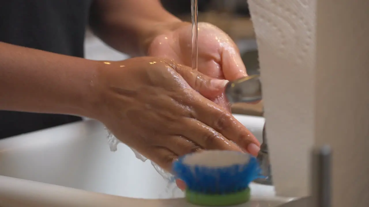 African American woman rinsing soap from her hands in the kitchen sink isolated close up