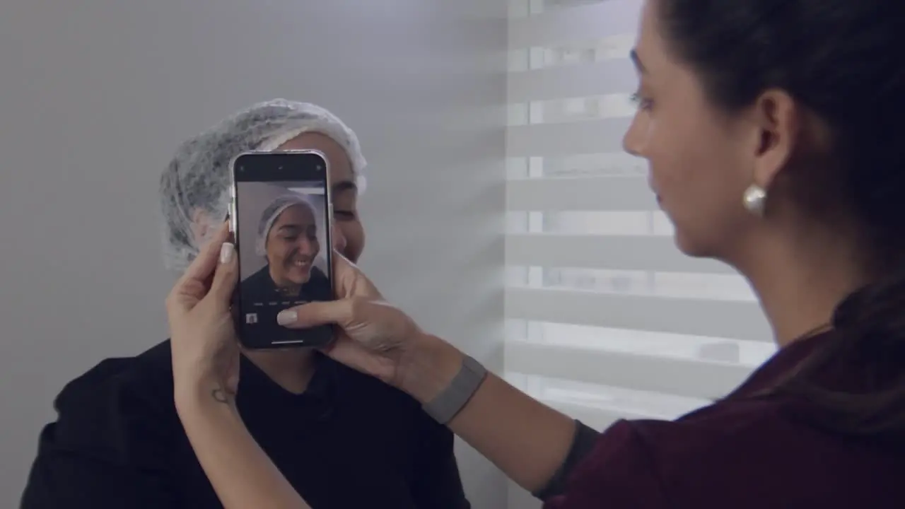 Nurse taking picture of a woman patient wearing bouffant cap in doctor's clinic slow motion