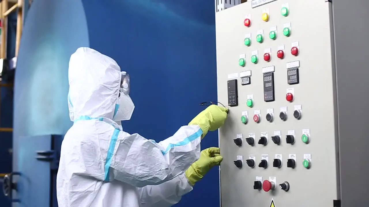 Waste burning energy factory worker in work clothes and with mask turning on generator switch of garbage incinerator