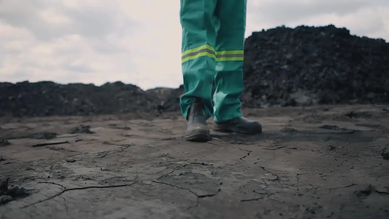 Amidst the barren landscape an industry worker stands on fractured mine soil a stark reminder of the environmental costs and challenges tied to resource extraction and industrial progress