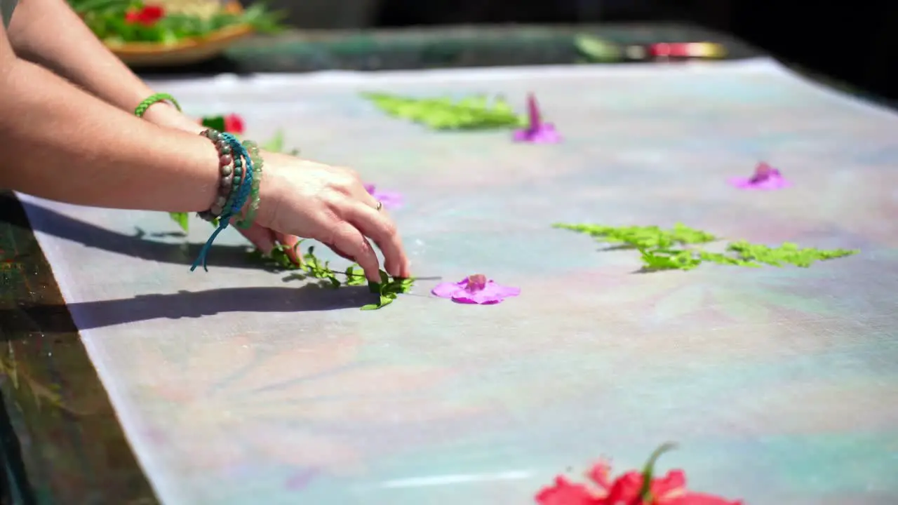 Clients learning homemade batik sarong pareo placing green leaves and flowers on white cloth Mahe Seychelles 25fps 1