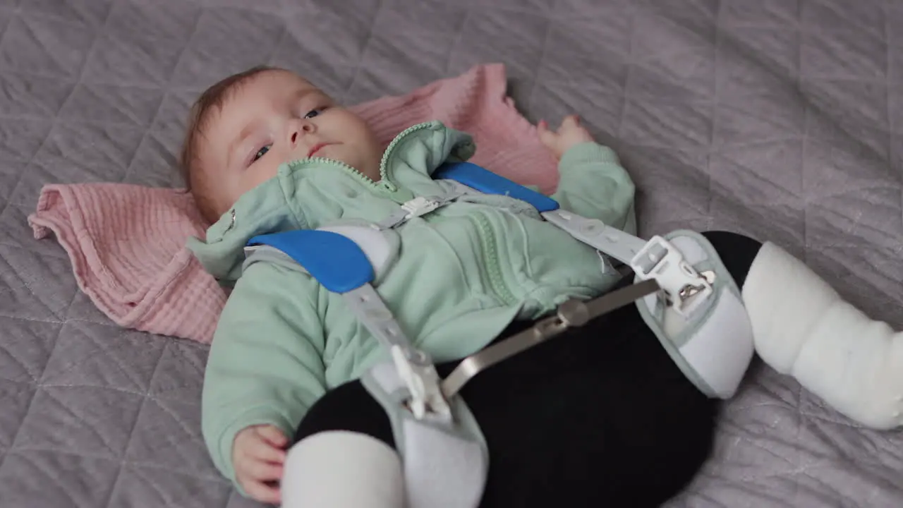 Baby girl lying on back wearing Pavlik Harness to correct Hip Dysplasia