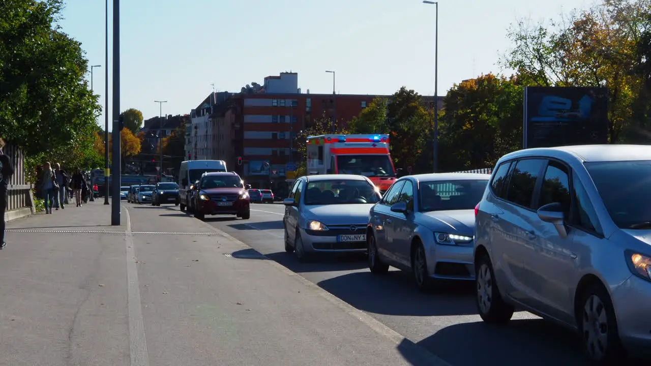 Car pull off the road to clear the way for ambulance with siren and flashing lights