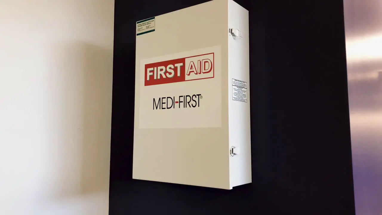 First-aid kit mounted to a purple wall in an office setting