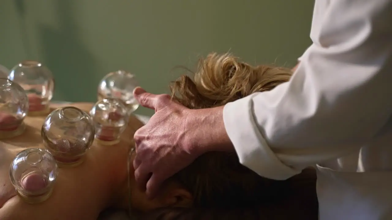 Therapist Massaging Female Patient Neck and Head During Cupping Therapy Session