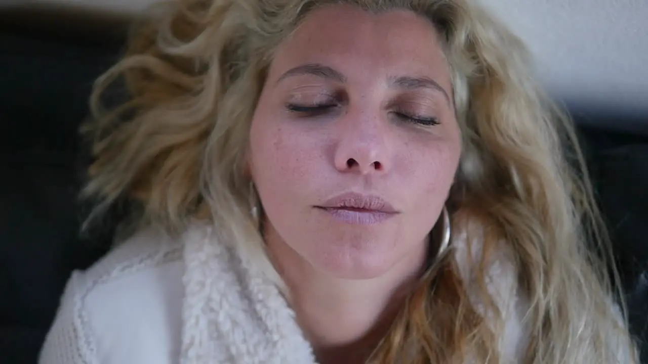 A sleeping sick woman turns her head and opens her eyes