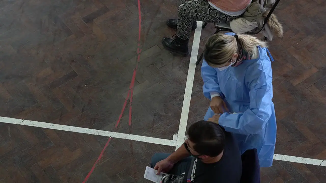 High angle view of a nurse applying a shot of COVID vaccine to a man in a makeshift vaccination center