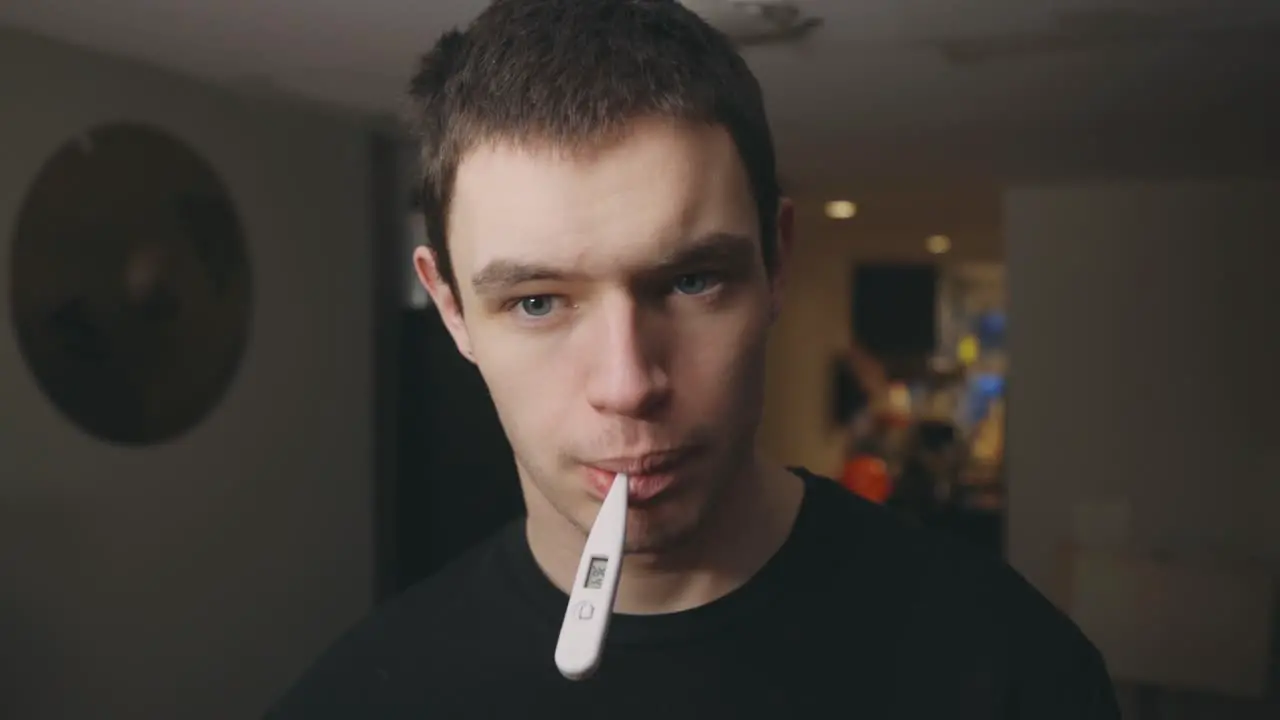 Young Man Checking His Body Temperature Using An Oral Digital Thermometer Health Care Concept Closeup Shot