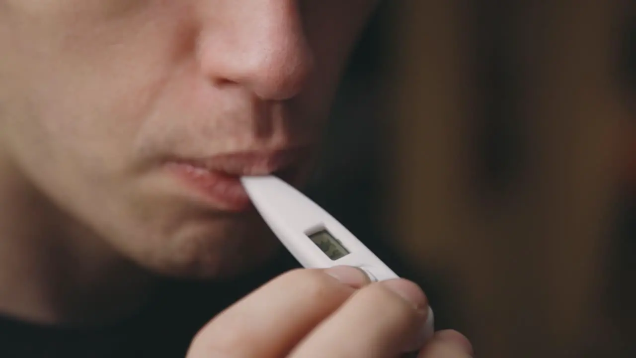 Cropped Face Of A Man Taking Temperature With A Digital Thermometer In Mouth