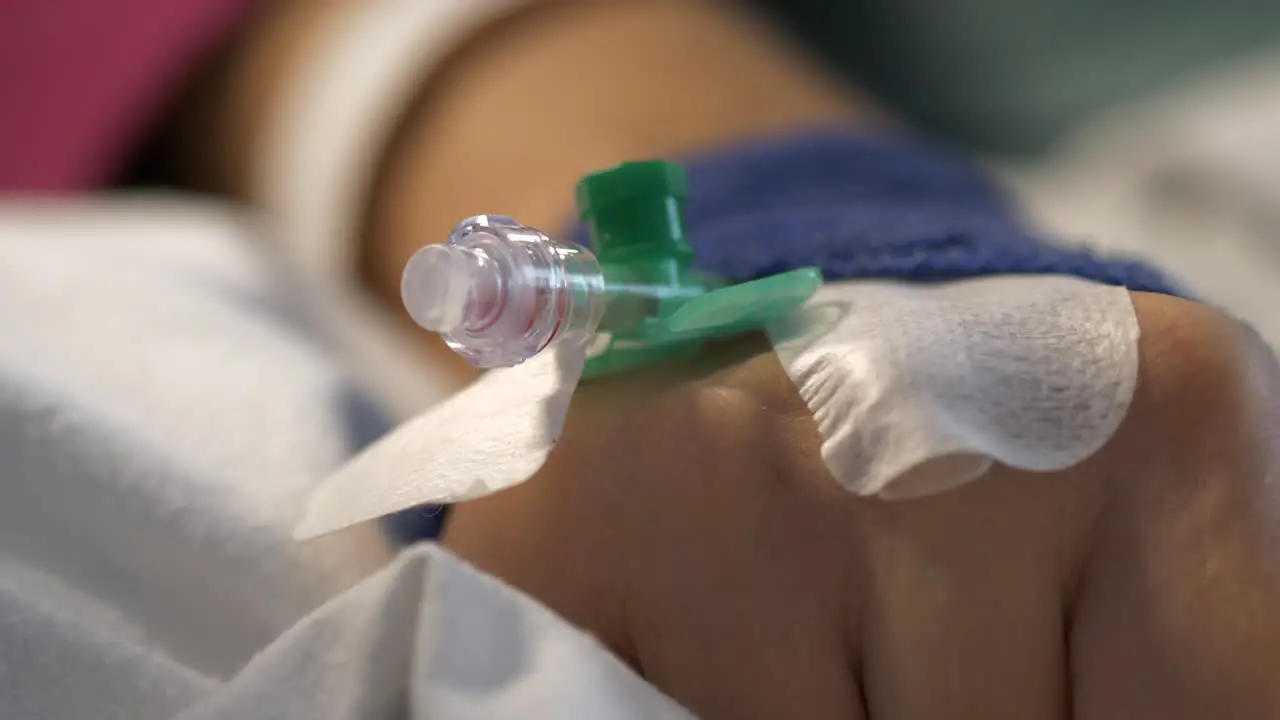 Hand of patient with drip in bed of hospital