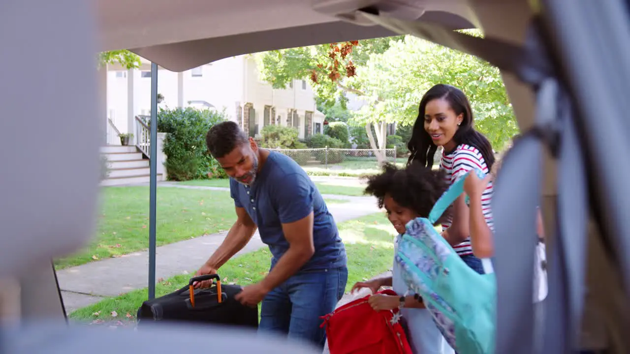 Family Leaving For Vacation Loading Luggage Into Car